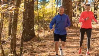 A Middle Aged Couple Goes For a Jog Through a Wooded Trail.