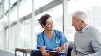 Nurse talking with older man at the hospital.