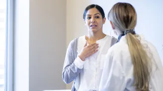 A young woman speaks to her female doctor.