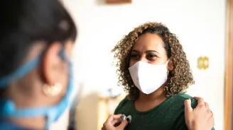 A Doctor Checks the Breathing of a Female Patient With a Stethoscope in an Office