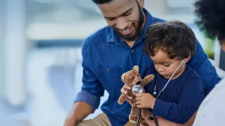 Father and son playing with teddy bear