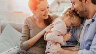 Mother and father embracing young daughter.