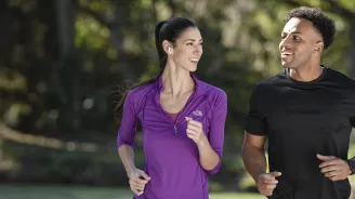 A Couple Runs Together in the Park While Sharing a Laugh