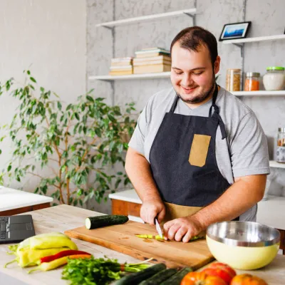 A man cutting up vegetables in his kitchen.
