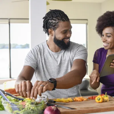 A couple making a salad from a recipe.