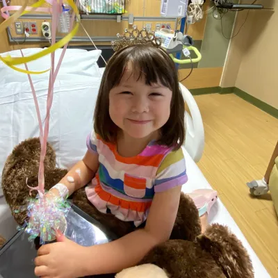 Faith Ahn smiles at the camera with balloons to celebrate leaving the hospital.