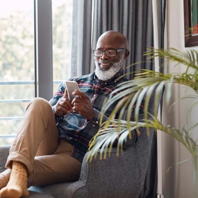 Older bearded man relaxing at home with phone