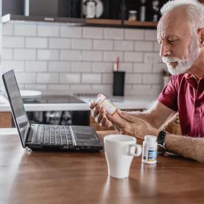 An older man requesting a prescription refill from his computer.