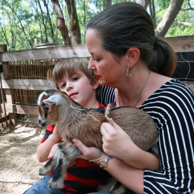 Cameron Munoz and one of her sons snuggle a baby goat at Puzzle Ranch in Sorrento, Florida.