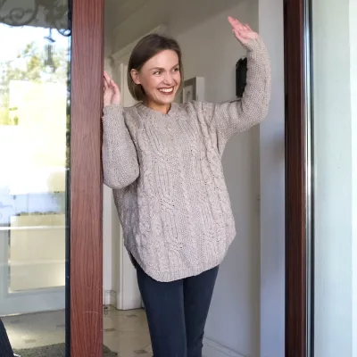 A woman waving at her neighbors from her porch. 