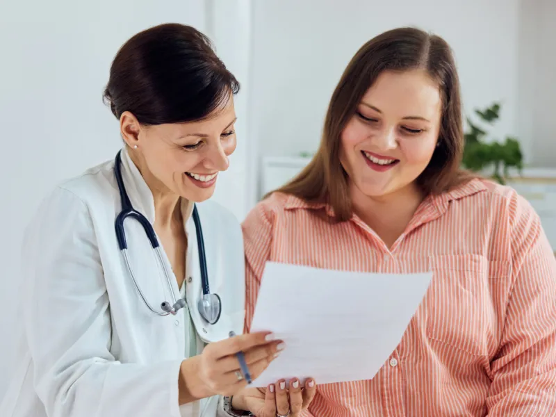 A Smiling Physician Goes Over a Chart with a Smiling Patient