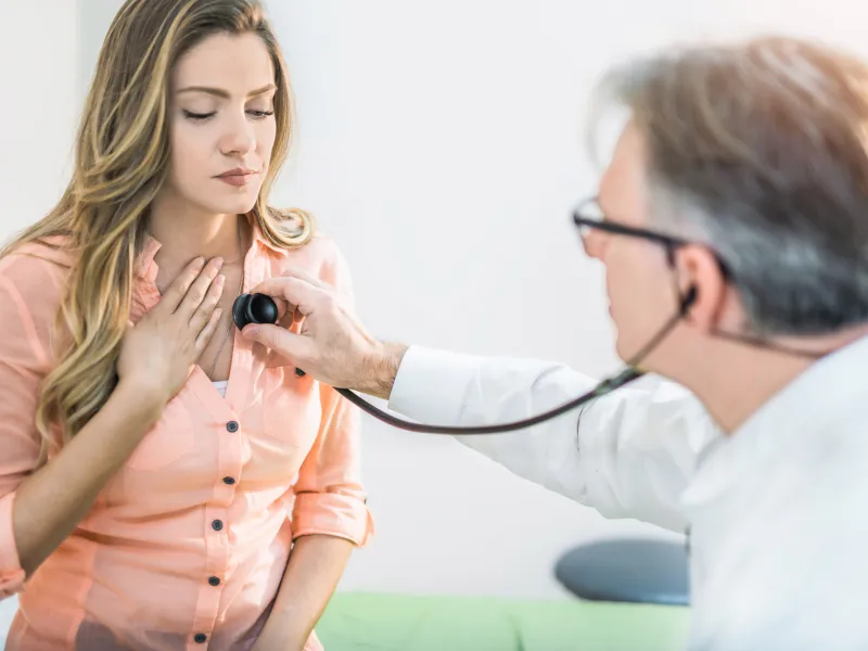 A doctor checking a woman's heart beat.