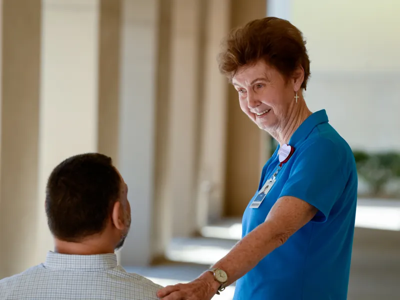 A Senior Woman Volunteer Comforts a Patient Outside.