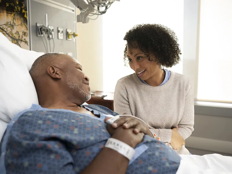 Family member comforting patient in hospital bed.