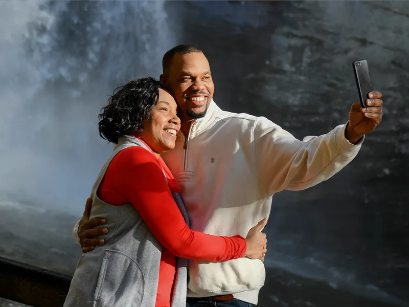 Couple taking a selfie in front of a waterfall.