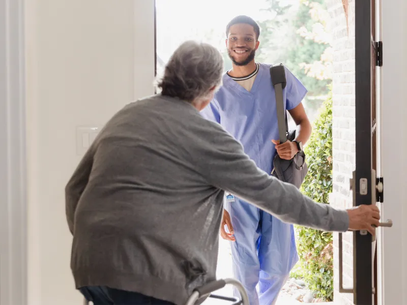 A Patient Opens Their Front Door to Allow a Therapist in Their Home