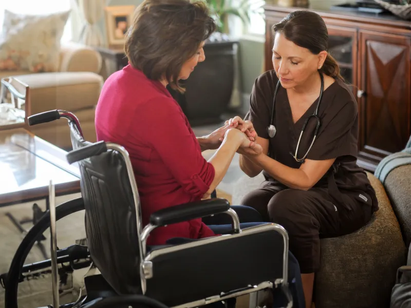 Woman in a wheelchair praying with a home care nurse.