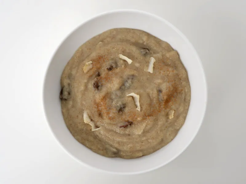 a bowl of hot cooked breakfast cereal mixed with raisins and shredded coconut