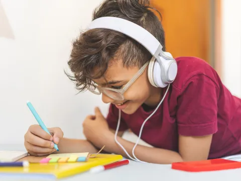 Boy working on schoolwork wearing headphones 
