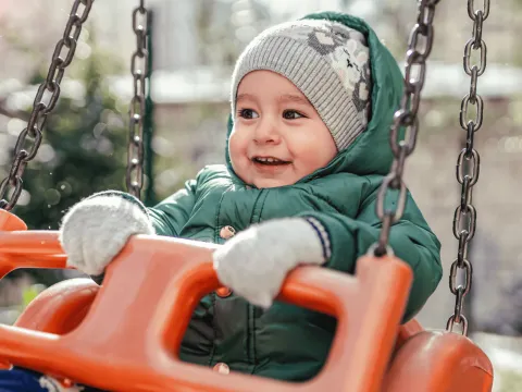 A Small Child in a Swing on a Playground. 