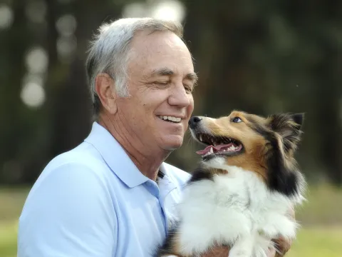 A Caucasian man plays with his pet Collie dog.