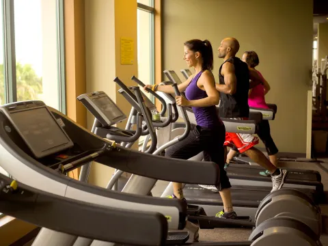 Three people running in different elliptical machines