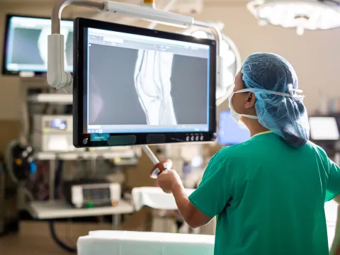 doctor in scrubs examining an x-ray in a surgical room