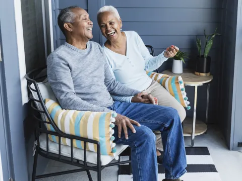 A couple laughing on their front porch together.