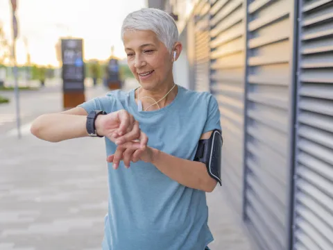A woman checking her heart rate on a run.