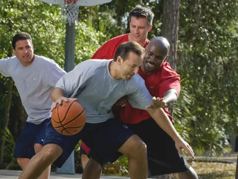 A group of men play basketball.
